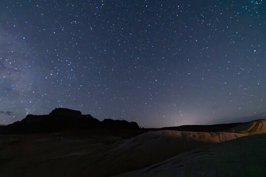 Starlit night sky over desert landscape with mountains in twilight, showcasing celestial beauty