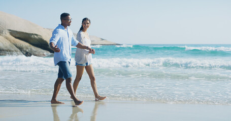 Beach, couple and holding hands with walking for holiday, travel vacation and bonding together by...