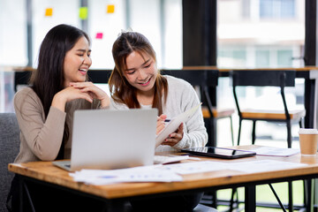 Two asian confident business people point to graphs and charts to analyze market data, balance sheet, account, net profit to plan new sales strategies to increase production capacity.	
