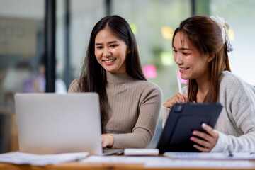 Two asian confident business people point to graphs and charts to analyze market data, balance sheet, account, net profit to plan new sales strategies to increase production capacity.	
