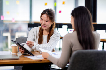 Two asian confident business people point to graphs and charts to analyze market data, balance sheet, account, net profit to plan new sales strategies to increase production capacity.	
