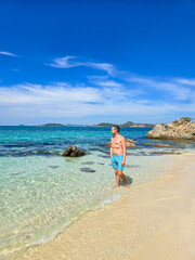 Strolling along the serene shores of Samae San Island, Thailand under a vibrant blue sky