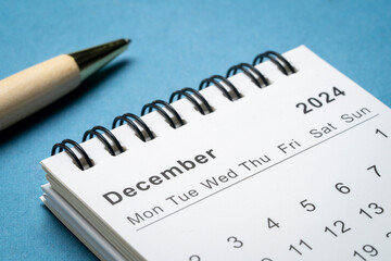 December 2024 - small spiral desktop calendar against abstract paper landscape, time and business concept