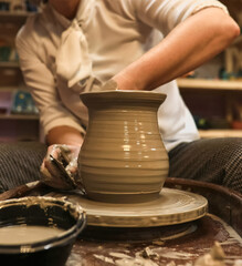 clay potter artist making pot shape on wheel pedestal.