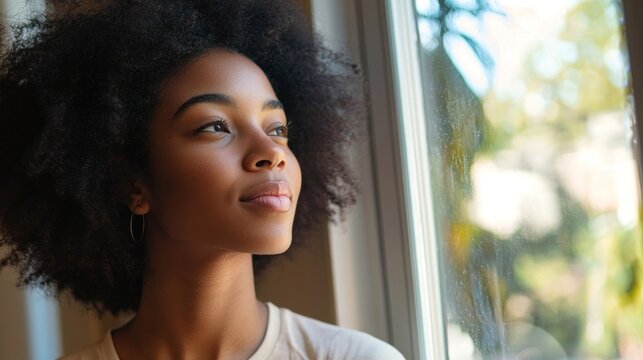 Woman looking hopeful and inspired while gazing out of a window