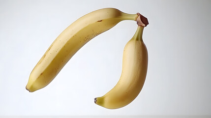 Two ripe bananas in mid-air on a light backdrop