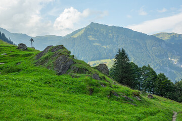 Lonesome wooden cross in Swiss Alps, contemplation atmosphere of mountain path