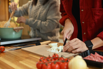 Man slicing onions on a cutting board for homemade pasta dish during the holiday season