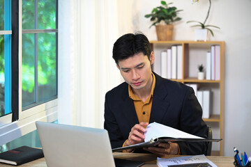 Fototapeta premium Serious male entrepreneur checking reports and preparing a presentation at workspace