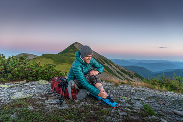 Man is Traveling with Backpack and has Problems with Sprained Ankle in the Mountains. Man with...