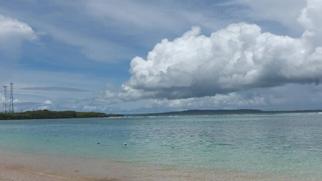 Thick, white cottony clouds over the water, with Tinian Island in the far distance. Northern Mariana Islands 