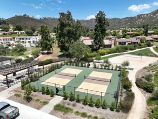 Aerial view of a pickle ball complex with courts beside a playground in a suburban park in San Diego