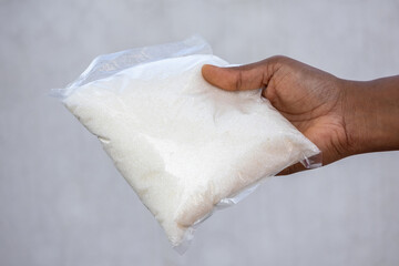 Female hand holds a packet of refined sugar, which is also called table sugar, granulated sugar, or regular sugar.