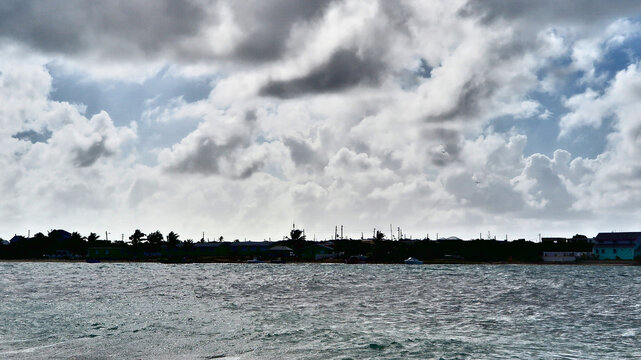 Stormy clouds rolling over Anguilla&rsquo;s coastline, creating a dramatic contrast with the choppy waters below.