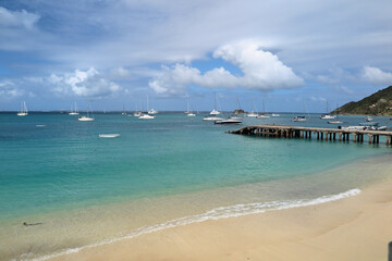 Anguilla’s turquoise beach waters dotted with boats under a bright blue sky, fringed by lush palm trees along the coast