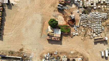 Aerial View of a Winding Dirt Road with Precast Concrete Materials and Scattered Trees