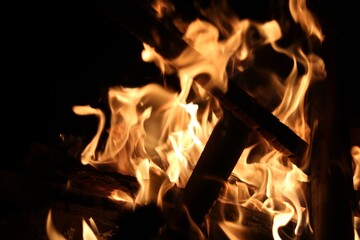 Close up image of burning embers in fire with charred pieces of wood