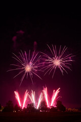 Fireworks explode in the night sky, illuminating the darkness with bright white and orange sparks, symbolizing the joy and celebration of New Year festivities.