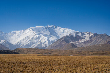 Colorful late summer landscape view of snowcapped Lenin Peak in Trans Alay mountain range, Sary...
