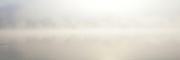 Obraz premium Peaceful morning mist rises over a tranquil lake, creating a soft white fog on the calm water's surface, glassy surface, reflective, serenity
