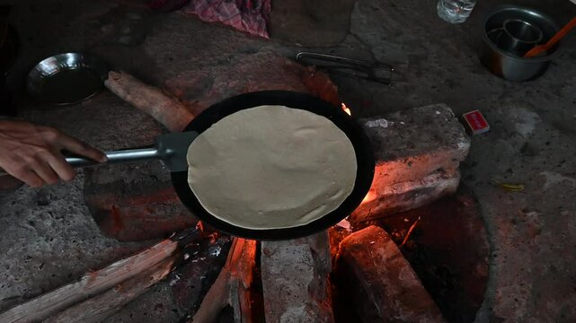 A village woman makes bread on the stove. cooking bread in clay stove , chula , makeing bread , roti , in village