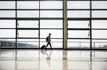 Fototapeta premium Man walking with suitcase at airport terminal.
