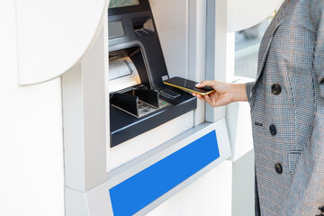 Person using smartphone for cash withdrawal at ATM.