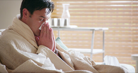 Living room, sinus and man with tissue, home and season for allergies, sick and sneezing with...