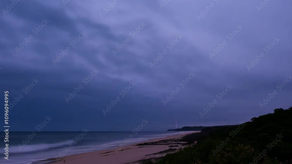Aufkleber The tranquil shoreline is adorned with soft waves lapping at the sandy beach under a twilight sky, while lush greenery frames the scene.