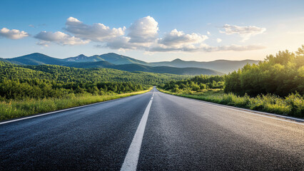 A long, straight road leading towards a mountain range at sunset.