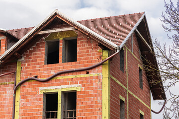 Naked house without facade. Visible red bricks, concrete crossbeams and external drainage. Roof already new