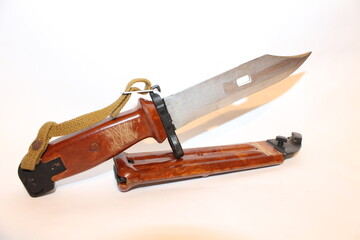 A combat knife is displayed with its hardwood handle and metal blade. The knife sits in its brown sheath, showcasing a tactical design suitable for outdoor activities and survival situations.