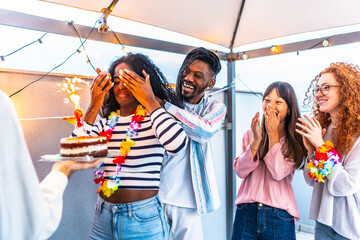 Woman with eyes covered receiving a birthday cake from friends