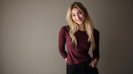 Fototapeta premium Portrait of a smiling young woman in a casual outfit against a neutral background, exuding warmth and approachability.