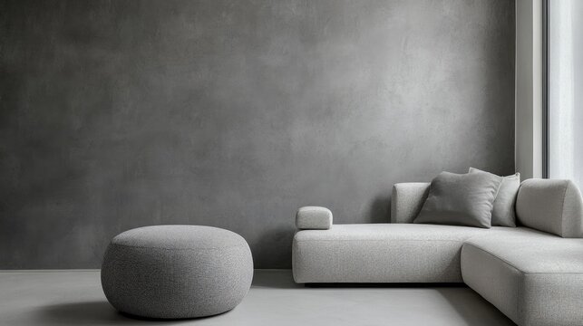 Scandinavian living room with a grey round pouf and minimalist sofa against a sleek grey wall, featuring ample empty space for customizable text.
