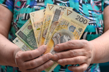Starsza pani emerytka trzyma w dłoniach polskie banknoty pln złoty 