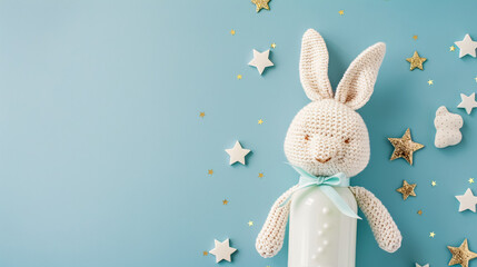 Baby Accessories Concept: Top view photo of a knitted bunny toy, milk bottle, and gold stars on an isolated pastel blue background with copyspace.