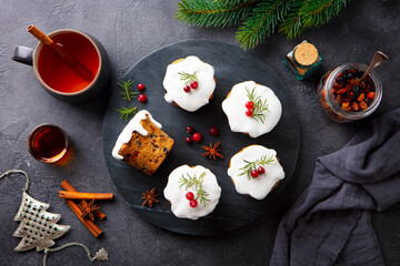 Christmas cakes, puddings on marble cutting board with cup of tea. Grey background. Top view.