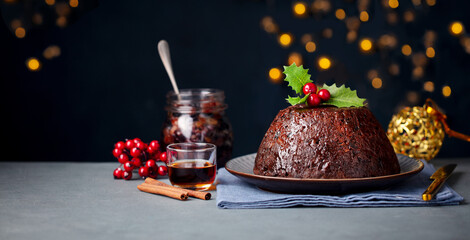Christmas pudding, fruit cake. Traditional festive dessert. Dark background with lights garland....