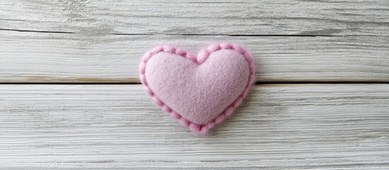 Felt pink heart decorative element on a textured grey wooden background for romantic or handmade themed designs