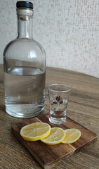 glass on the table, bottle on the table, glass with bottle on the table, table setting, table setting for a holiday, colorless drink, bottle with transparent drink, snack with lemon