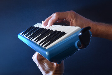 Man prepared to play melodica in hands with blue background