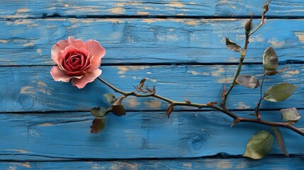 Delicate rose and love ornament on a weathered blue wooden background, ideal for romantic themes and customizable text space.