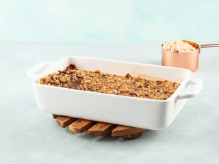 Vegan oatmeal banana cake in white baking pan on turquoise © tenkende