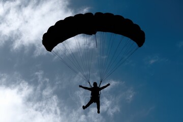 A silhouette of a skydiver descending with an open parachute.