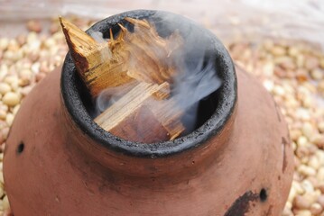 close up of a pot with wooden fire with smoke 
