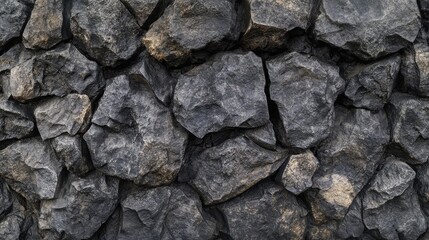 Textured black concrete stone wall featuring rugged, irregular stones in various sizes, ideal for use as a backdrop in design projects, presentations, or artistic endeavors.