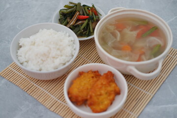 Creamy soup in a white bowl, with delicious side dishes