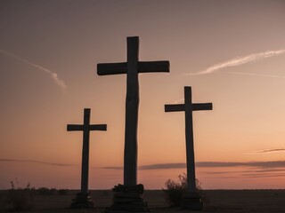 Three crosses are standing in a field at sunset.