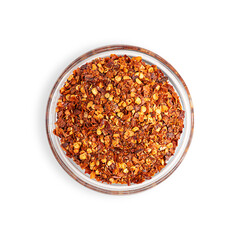 Top view of dried spicy red hot chili pepper flakes with seeds served in glass bowl cultivated for pungency used as organic ingredient in culinary as spice to add heat for capsaicin isolated on white